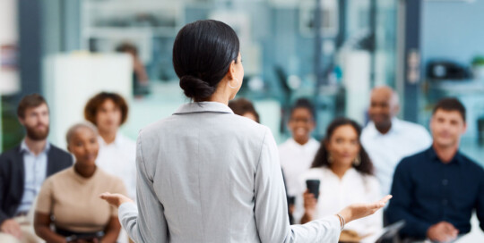 Woman speaking in front of business professionals