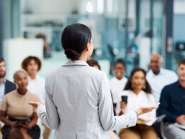 Woman speaking in front of business professionals